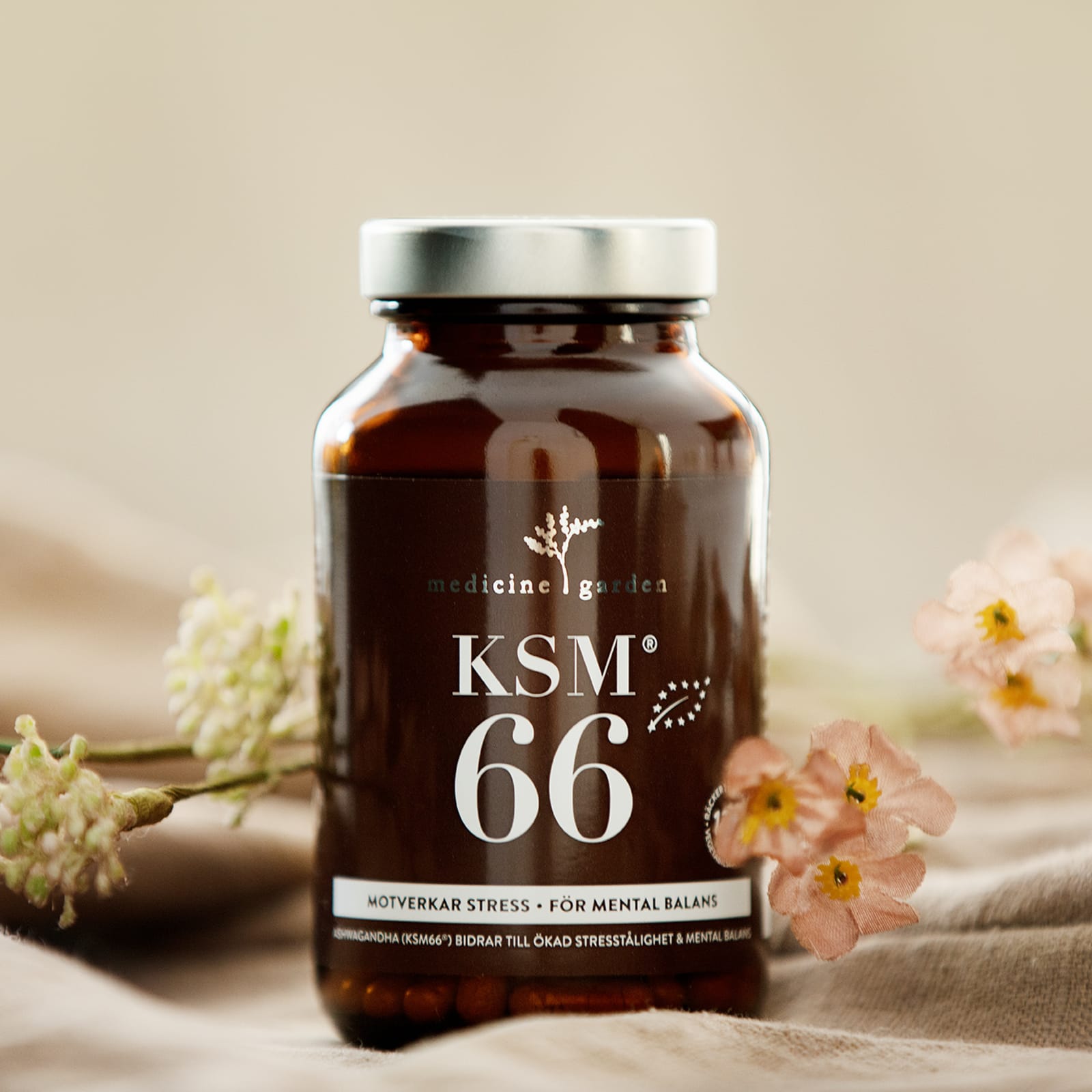 Medicine Garden KSM66 Ashwagandha ved siden av lyserøde blomster