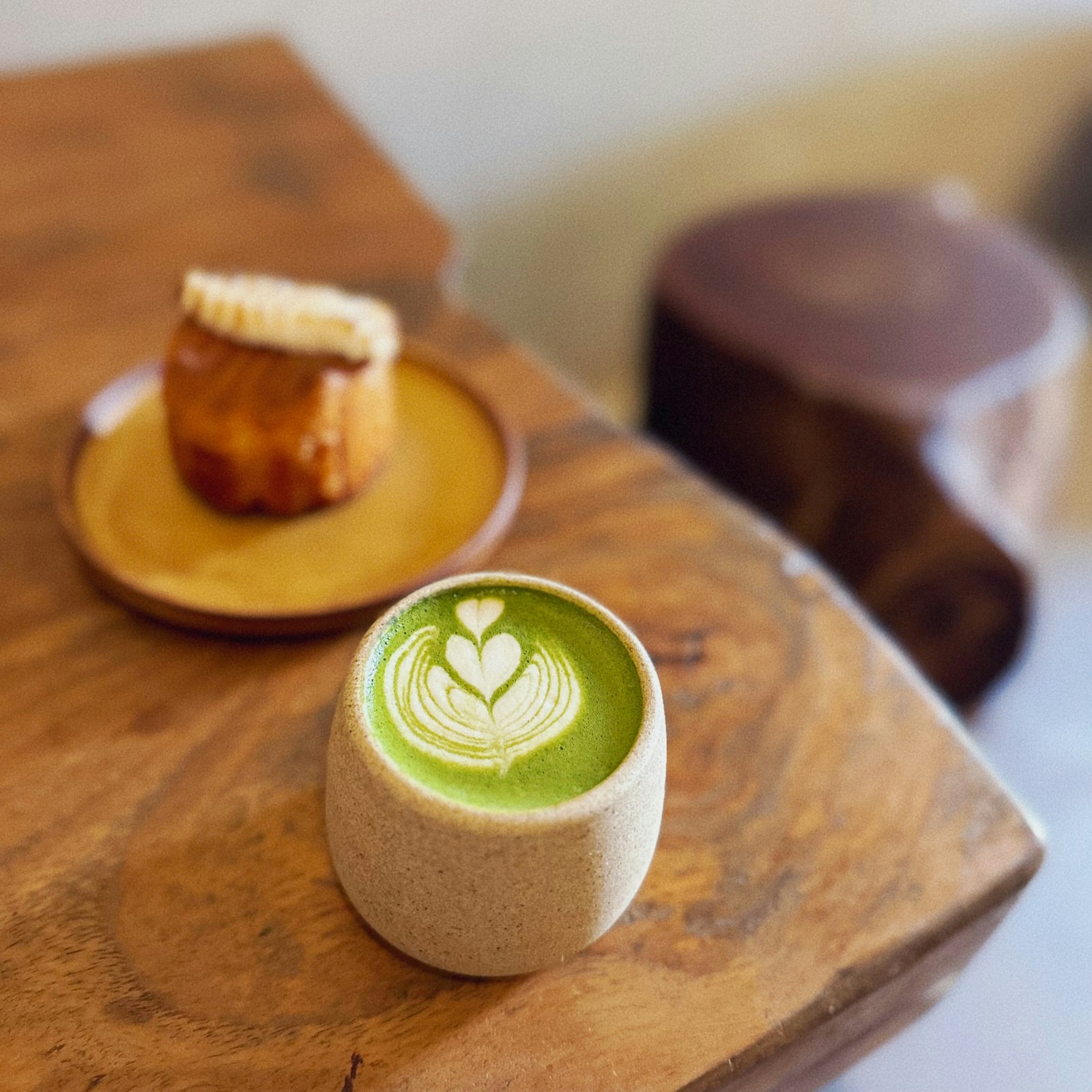 Kopp med matcha latte med mønster i skummet på et trebord