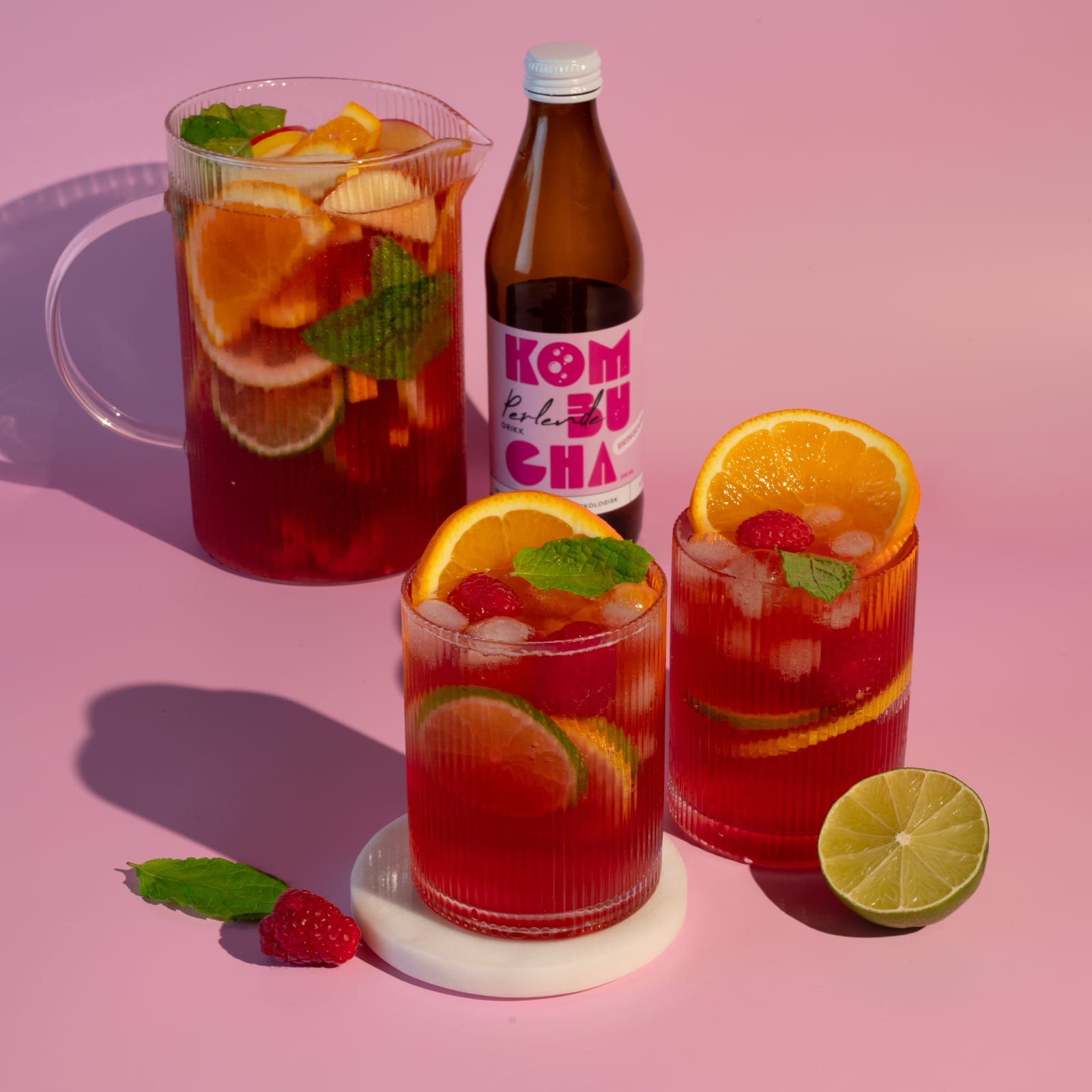 Kombucha-sangria i mugge og glass med appelsin, lime og bringebær